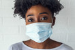 Portrait of young African-American woman wearing disposable medical face mask
