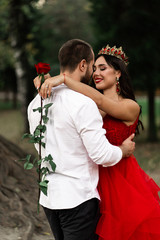 Wall Mural - Beautiful romantic couple kiss closeup. Attractive young woman in red dress and crown with handsome man in white shirt are in love. Happy Saint Valentine's Day. Pregnant and wedding concept.