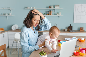 stressed mother with her baby working at home