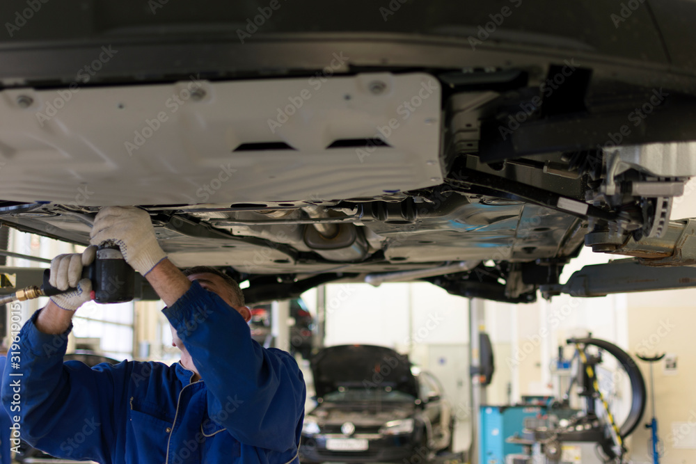 The car is lifted on a lift in a car service for repair. A professional ...