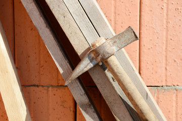 hammer hangs on wooden slats at construction site in front of house wall