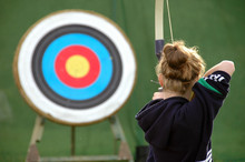 Rear View Of Girl Aiming At Target With Bow And Arrow