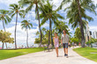 © Maridav - Honolulu city travel tourists couple walking on Waikiki beach boardwalk visiting Oahu island, USA summer travel holidays. Happy man and woman lifestyle.