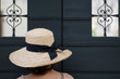 Woman with a Straw Hat close to a Door with Two Windows.