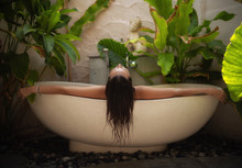 Woman Relaxing In Outdoor Bath With Tropical Leaves At Bali