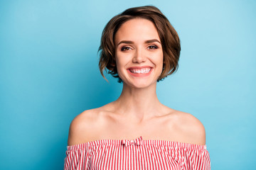 Closeup photo of beautiful pretty lady short bob hairdo positive good mood easy-going person wear pink white striped shirt naked shoulders isolated blue color background