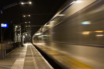 Wall Mural - Blurred train by motion at night at station Arnhem south, Netherlands