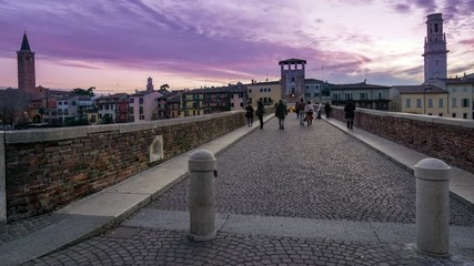 Wall Mural - Sunset in Verona, Italy. Time lapse of people crossing old roman bridge Ponte Pietra. Veneto	