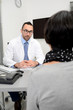 © W PRODUCTION - handsome male doctor with a female patient in hospital consultation office desk
