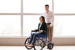 © Pixel-Shot - Handicapped young woman in wheelchair and her husband near window