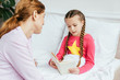 © LIGHTFIELD STUDIOS - cute daughter reading book to mother in bed