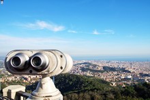 Hand-Held Telescope Against Cityscape And Blue Sky