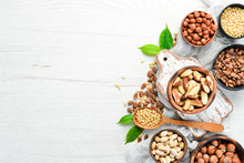 Assortment Of Nuts In Bowls On White Wooden Background. Free Space For Your Text. Top View.