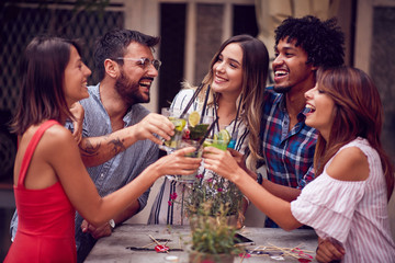 Wall Mural - Group of young people with cocktails  having fun in nightclub celebrating. Fun, friendship, celebration concept.