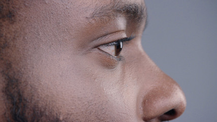 Close-up profile of handsome confident african american man with a beard looking forward isolated on grey background.