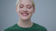 Portrait of beautiful young blonde woman crying of happiness with tears smiling on camera in the studio on grey background.