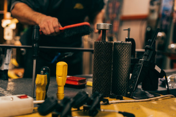 Wall Mural - selective focus of repair tools and worker using brush on ski in repair shop