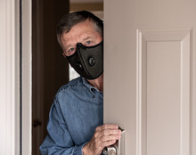 Concerned And Worried Man Wearing A Protective Breathing Mask Against Flu And Coronavirus And Greeting Visitor