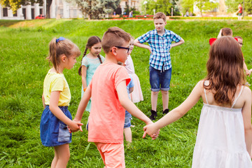 Wall Mural - Group of children holding hands and dancing in circle on green lawn