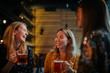 © chika_milan - Group of friends drinking beer, chatting. Night out. Pub interior.