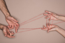 Top View Of Man And Woman Holding Red String On Beige Background