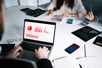 Wall Mural - Anonymous employee browsing laptop with charts on screen