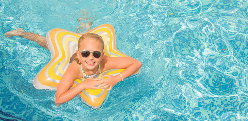 Pretty little girl in swimming pool, summer vacations.