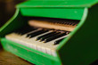 The old toy piano. Wooden green musical instrument for preschool age. Vintage toy for children. Side view. Selective focus. Eye level shooting.