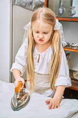 cute little girl ironing clothes in the kitchen. child assistant mistress