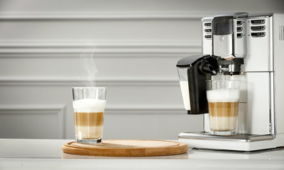 Poster - Fresh hot caffe latte and white coffee machine in home interior. 