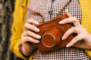 Woman with in the park with retro photo camera. Fashionable autumn clothes in orange mustard tones