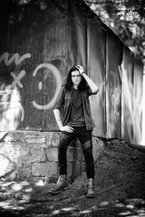 Wall Mural - a black-and-white photo of a young man with long, dark hair and brown eyes, a face with freckles, walking down the street in a stylish shirt and jeans,in a Cagle style, in a sad mood