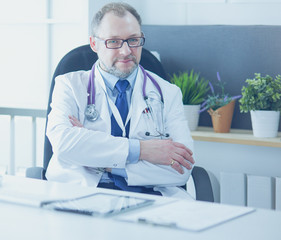 Portrait of senior doctor in office sitting at the desk