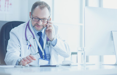 Portrait of senior doctor in office sitting at the desk