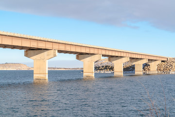 Stringer bridge crossing over a blue lake and connecting snowy rocky terrains