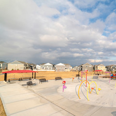 Wall Mural - Square Colorful childrens playground against houses and overcast blue sky in winter