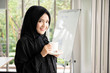 © DG PhotoStock - Beautiful Muslim business woman in black dress drinking a cup of coffee in the office close up.
