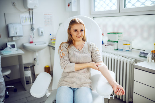 beautiful brave smiling caucasian blonde in sweater sitting in chair in lab and holding cotton on ve