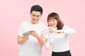 Young couple with mobile phones on color background