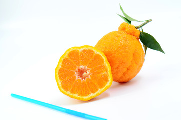 Cut Mandarin and blue straw on white background