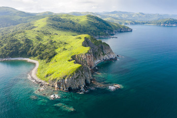 aerial view of green rocky coastline and clean turquoise sea in asia. cape azaryev at gamov peninsul
