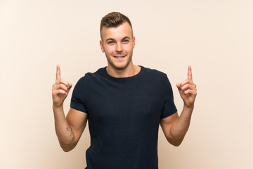 Wall Mural - Young handsome blonde man over isolated background pointing up a great idea