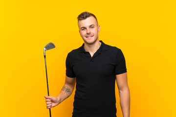 Golfer player man over isolated yellow background smiling a lot