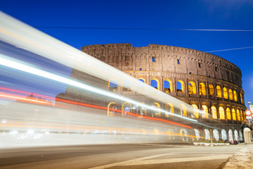 Fototapete - Rome, Italy - Jan 2, 2020: Colosseum at night with colorful blurred traffic lights