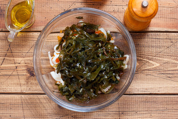 Step by step preparation of salad with seaweed, squid and pumpkin, step 4 - adding pickled cabbage to the salad, selective focus, horizontal