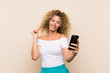 © luismolinero - Young blonde woman with curly hair over isolated background making a selfie