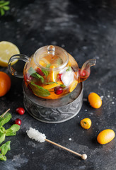 Wall Mural - Fruit tea with mint, oranges and cranberry on dark stone background. A cup of hot tea