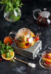 Wall Mural - Fruit tea with mint, oranges and cranberry on dark stone background. A cup of hot tea