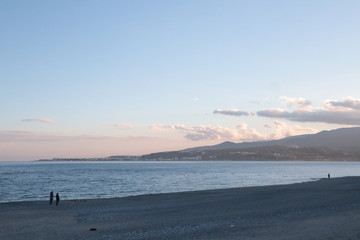 Persone che camminano sulla spiaggia al tramonto