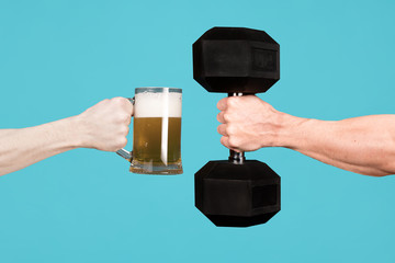 Men are holding out each other a glass of beer and a large dumbbell